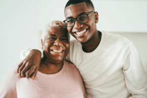 Smiling older woman with a younger man embracing indoors