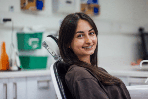 Smiling young woman wearing metal braces while seated in an orthodontic chair